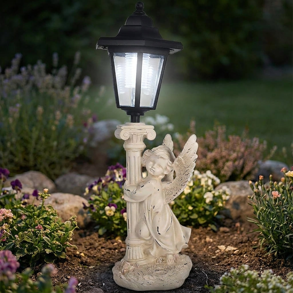 Solar-powered angel statue lamp with glowing hexagonal lantern top standing among garden flowers at dusk
