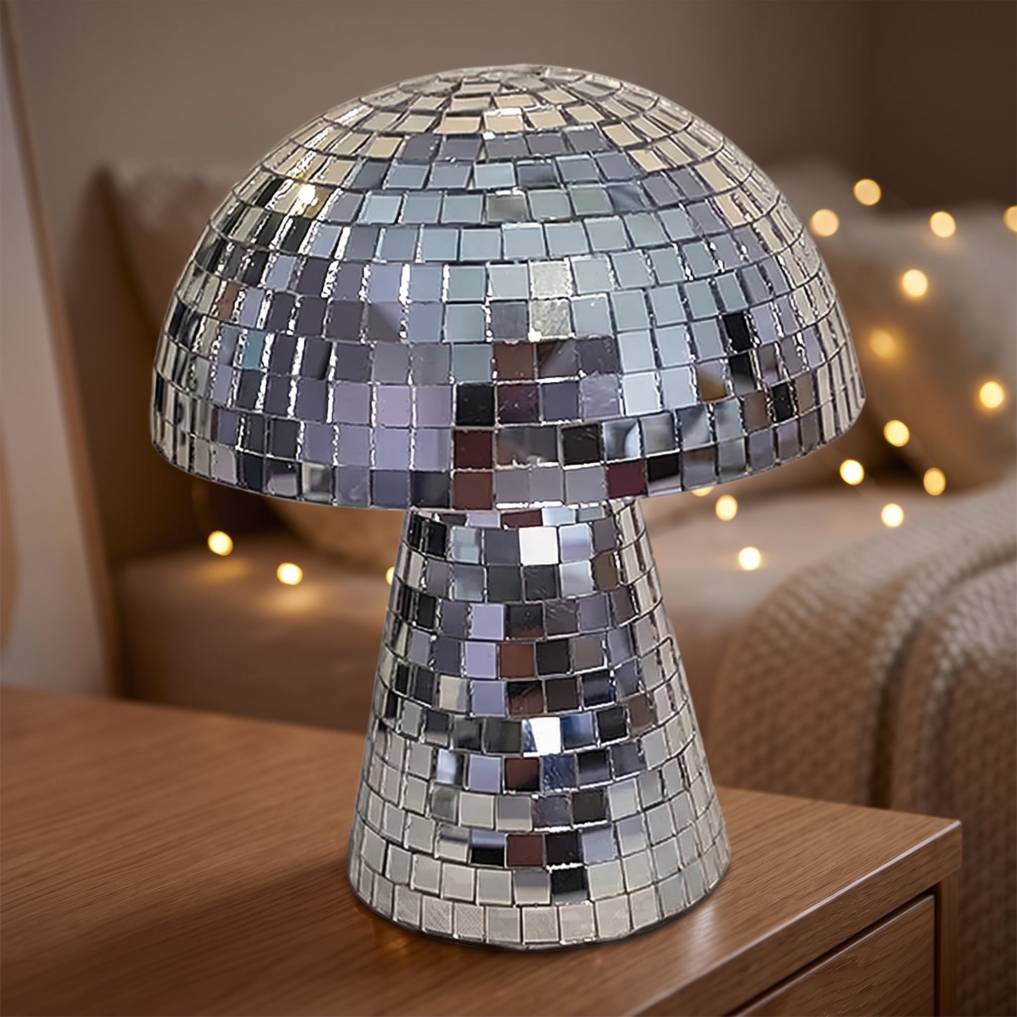 Mirrored disco mushroom ornament in silver mosaic glass tiles, displayed on a wooden dresser in a warmly lit bedroom