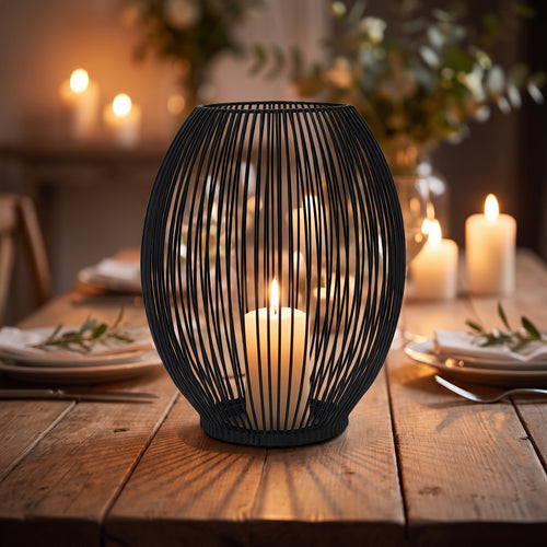 Black vintage iron wire cage lantern candle holder with a lit candle on a rustic wooden dining table