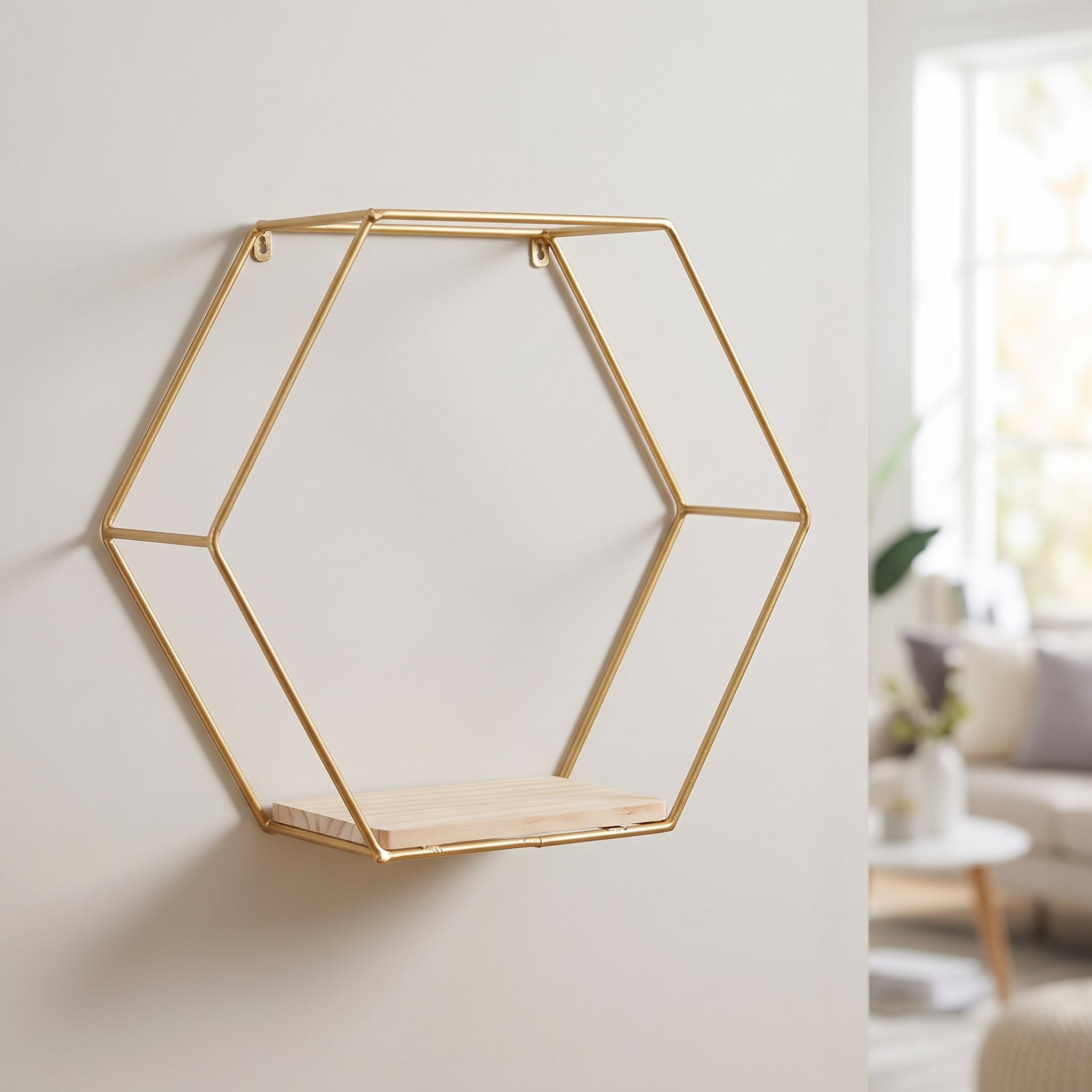 Gold hexagon floating wall shelf with wood shelf base mounted on a living room wall